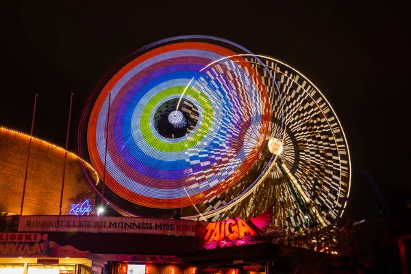 Helsinki, Finland - 19 October 2019: The Carnival of Light event at the Linnanmaki amusement park. Ride Ferris Wheel Rinkeli and Kehra in motion, night illumination, long exposure. — Stock Photo, Image