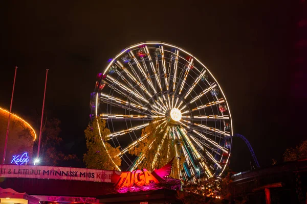Helsinki, Finland - 19 October 2019: The Carnival of Light event at the Linnanmaki amusement park. Ride Ferris Wheel Rinkeli in motion, night illumination. — ストック写真