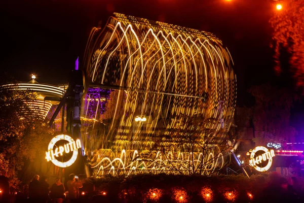 Helsinki, Finlândia - 19 de outubro de 2019: O Carnaval de Luz no parque de diversões Linnanmaki. Passeios Kieputin, Ketjukaruselli e Vuoristorata em movimento. Iluminação noturna, exposição longa . — Fotografia de Stock