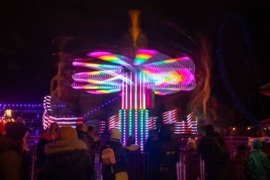 Lunaparkta hareketli bulanık renkli bir atlıkarınca, gece aydınlatması. Uzun pozlama.