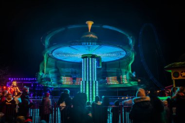 Lunaparkta hareketli bulanık renkli bir atlıkarınca, gece aydınlatması. Uzun pozlama.