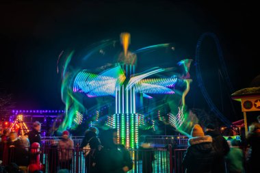 Lunaparkta hareketli bulanık renkli bir atlıkarınca, gece aydınlatması. Uzun pozlama.