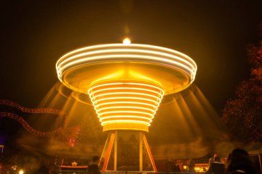 Lunaparkta hareketli bulanık renkli bir atlıkarınca, gece aydınlatması. Uzun pozlama.