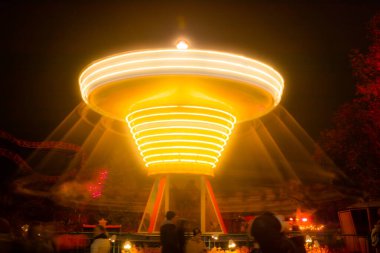 Lunaparkta hareketli bulanık renkli bir atlıkarınca, gece aydınlatması. Uzun pozlama.