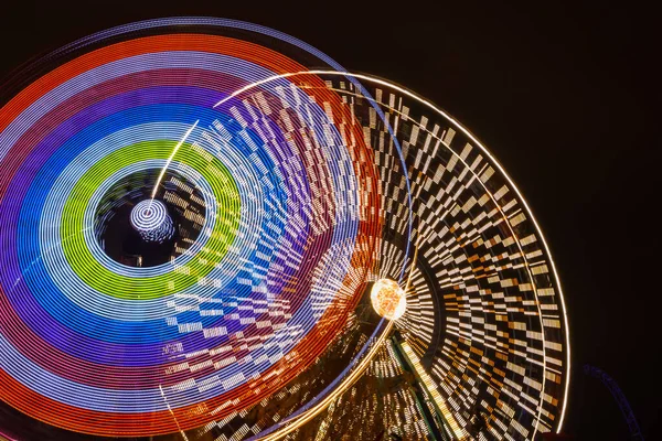 Zwei Fahrgeschäfte in Bewegung im Vergnügungspark, nächtliche Beleuchtung. Langzeitbelichtung. — Stockfoto