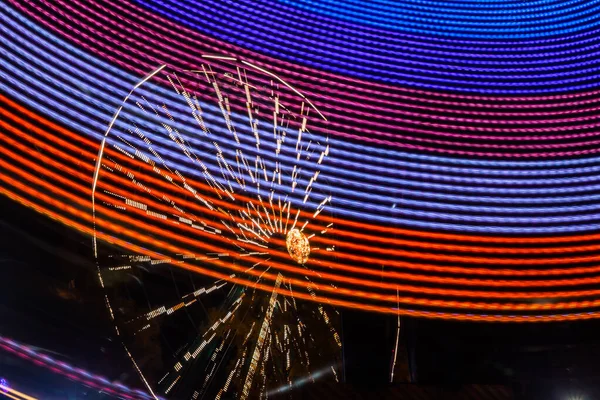 Deux balades en mouvement dans un parc d'attractions, illumination nocturne. Longue exposition . — Photo