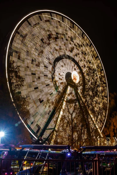 Roda gigante em movimento no parque de diversões, iluminação noturna. Exposição longa . — Fotografia de Stock