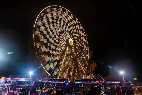 Rueda de la fortuna en movimiento en el parque de atracciones, iluminación nocturna. Larga exposición . —  Fotos de Stock