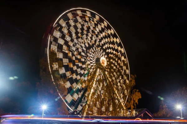 Grande roue en mouvement au parc d'attractions, illumination nocturne. Longue exposition . — Photo