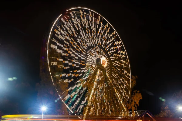 Ruské kolo v pohybu v zábavním parku, noční osvětlení. Dlouhá expozice. — Stock fotografie