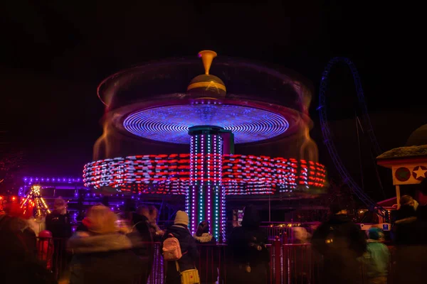 Una giostra sfocata colorata in movimento al parco divertimenti, illuminazione notturna. Lunga esposizione . — Foto Stock