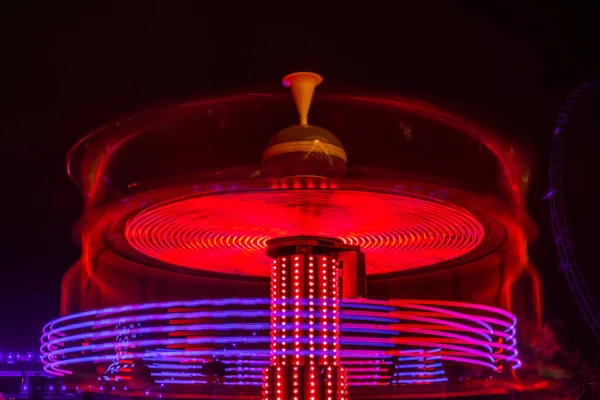 Un carrousel coloré flou en mouvement au parc d'attractions, illumination nocturne. Longue exposition . — Photo