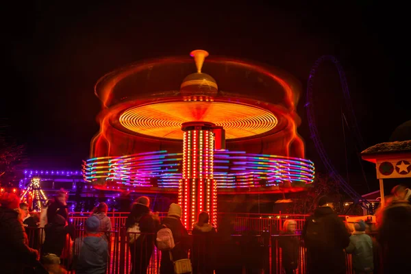 Una giostra sfocata colorata in movimento al parco divertimenti, illuminazione notturna. Lunga esposizione . — Foto Stock