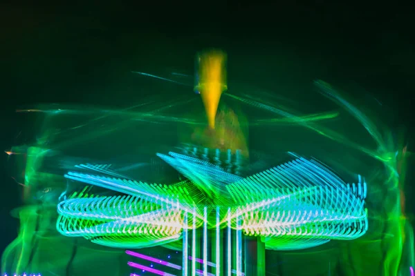 一个模糊的五彩缤纷的旋转木马在游乐园，夜间照明。 长期接触. — 图库照片