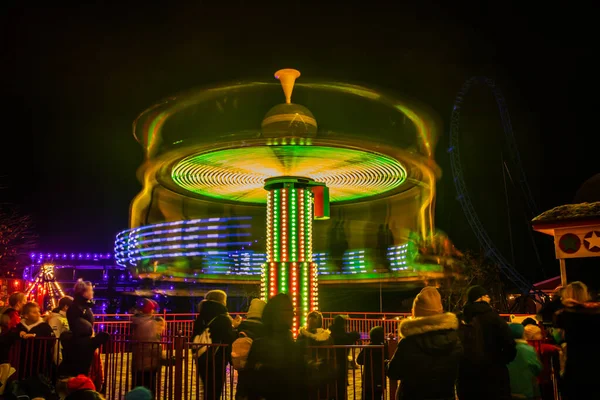 Una giostra sfocata colorata in movimento al parco divertimenti, illuminazione notturna. Lunga esposizione . — Foto Stock