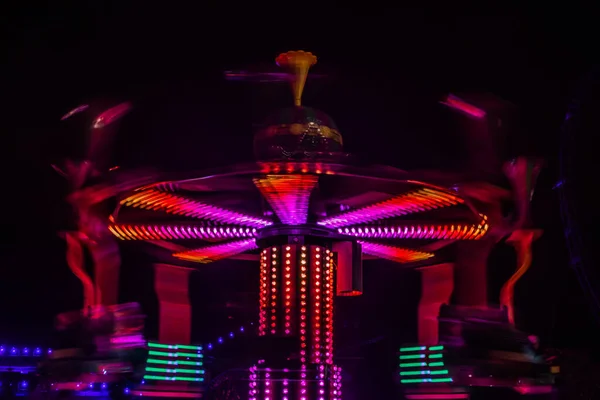 Een wazige kleurrijke draaimolen in beweging in het pretpark, nachtverlichting. Lange blootstelling. — Stockfoto