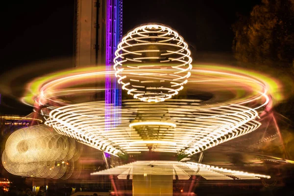 Un carrusel colorido borroso en movimiento en el parque de atracciones, iluminación nocturna. Larga exposición . — Foto de Stock