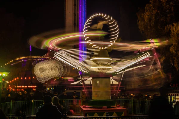Un carrousel coloré flou en mouvement au parc d'attractions, illumination nocturne. Longue exposition . — Photo