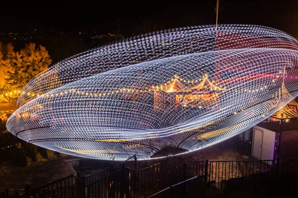 Un carrousel coloré flou en mouvement au parc d'attractions, illumination nocturne. Longue exposition . — Photo