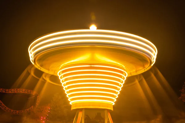 Een wazige kleurrijke draaimolen in beweging in het pretpark, nachtverlichting. Lange blootstelling. — Stockfoto