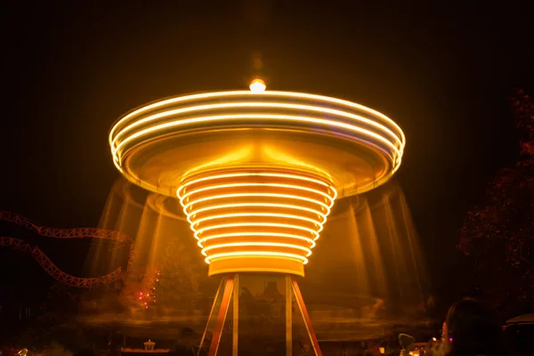 Un carusel colorat înceţoşat în mişcare în parcul de distracţii, iluminare nocturnă. Expunere lungă . — Fotografie, imagine de stoc