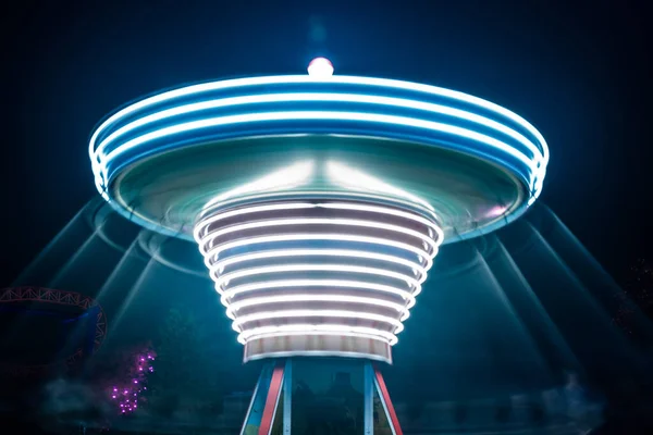 A blurry colorful carousel in motion at the amusement park, night illumination. Long exposure. — Stock Photo, Image