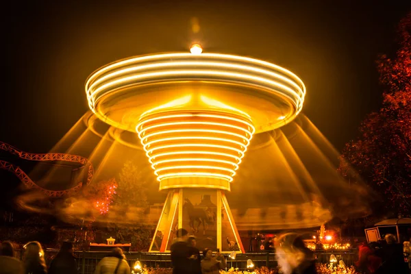 Una giostra sfocata colorata in movimento al parco divertimenti, illuminazione notturna. Lunga esposizione . — Foto Stock