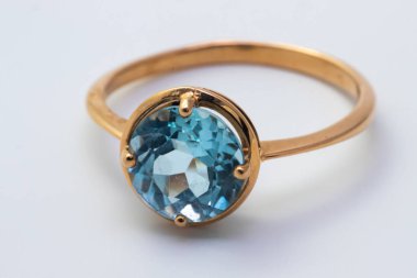 Beyaz arka planda izole edilmiş mavi değerli taşlı güzel altın bir yüzük.