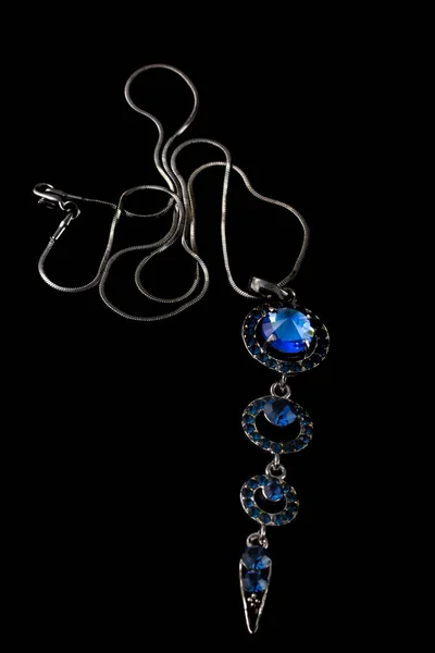 Bellissimo ciondolo in argento con pietre blu e catena isolata su sfondo nero — Foto Stock