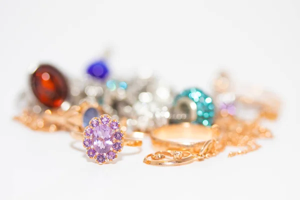 Коллекция ювелирных изделий с красивым золотым кольцом с фиолетовым камнем на белом фоне — стоковое фото