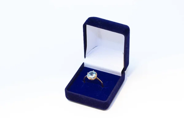 Bague dorée avec pierre précieuse dans une boîte à bijoux bleue sur fond blanc Photos De Stock Libres De Droits