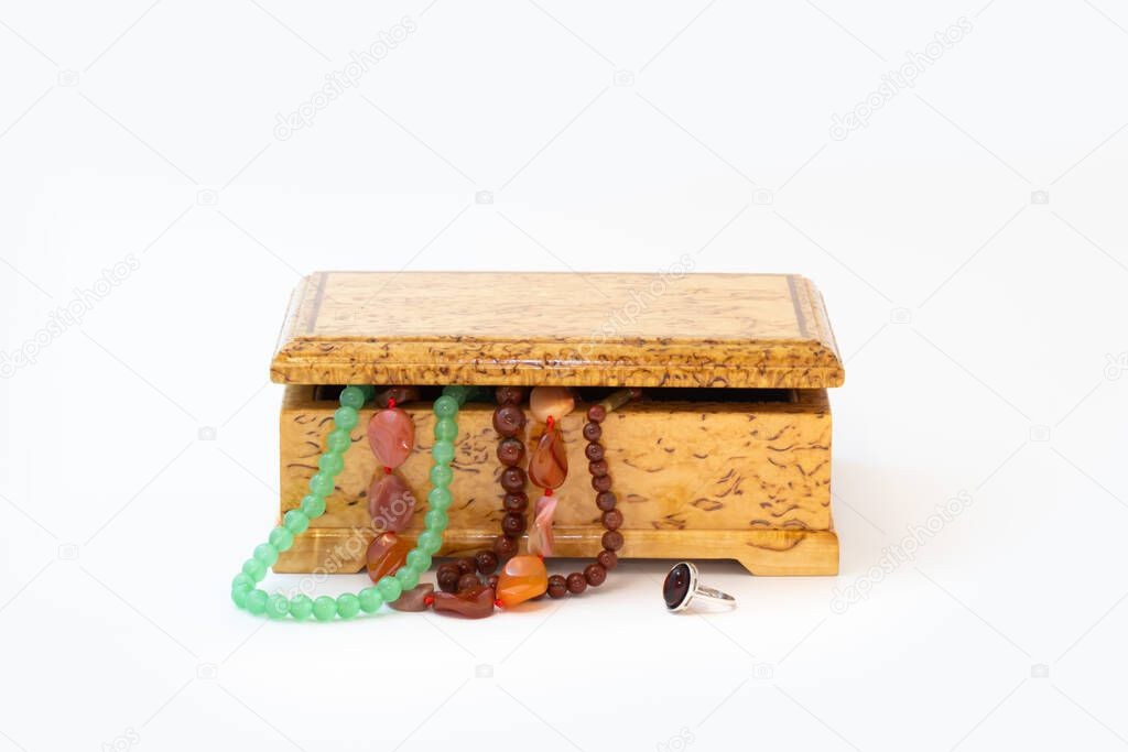 Jasper, agate and nephritis beads in wooden jewelry box and silver ring with amber isolated on white background