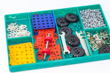 İçinde farklı renkte metal yapıcı detayları ve beyaz arkaplanda tornavida bulunan yeşil plastik kutu