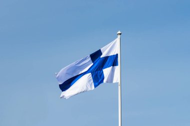 Mavi gökyüzüne karşı esen Finlandiya ulusal bayrağı