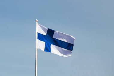 Mavi gökyüzüne karşı esen Finlandiya ulusal bayrağı