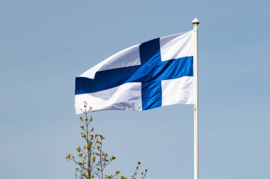 Mavi gökyüzüne karşı esen Finlandiya ulusal bayrağı