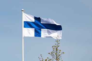 Mavi gökyüzüne karşı esen Finlandiya ulusal bayrağı