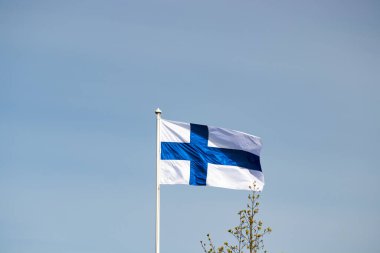 Mavi gökyüzüne karşı esen Finlandiya ulusal bayrağı
