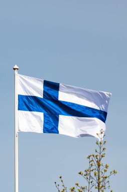 Mavi gökyüzüne karşı esen Finlandiya ulusal bayrağı