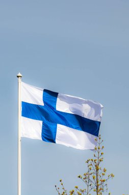 Mavi gökyüzüne karşı esen Finlandiya ulusal bayrağı