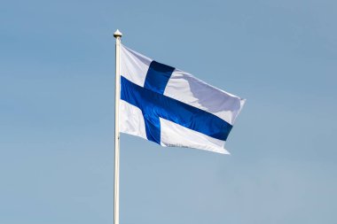 Mavi gökyüzüne karşı esen Finlandiya ulusal bayrağı