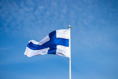 Mavi gökyüzüne karşı esen Finlandiya ulusal bayrağı