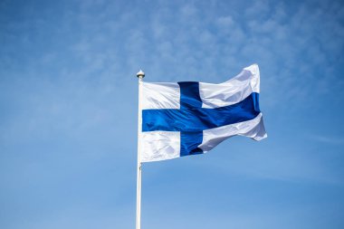 Mavi gökyüzüne karşı esen Finlandiya ulusal bayrağı