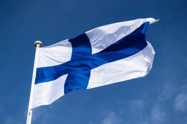 Mavi gökyüzüne karşı esen Finlandiya ulusal bayrağı
