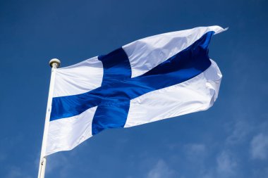 Finnish national flag on the wind against the blue sky clipart