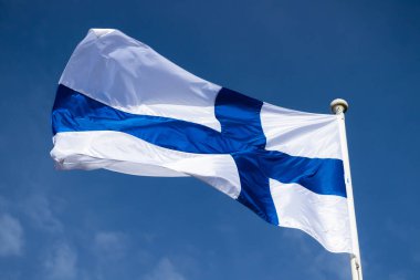 Mavi gökyüzüne karşı esen Finlandiya ulusal bayrağı