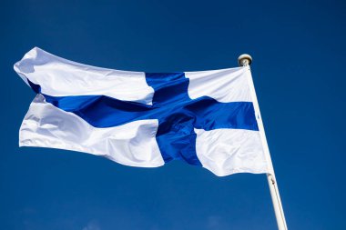 Mavi gökyüzüne karşı esen Finlandiya ulusal bayrağı