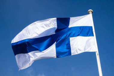 Mavi gökyüzüne karşı esen Finlandiya ulusal bayrağı