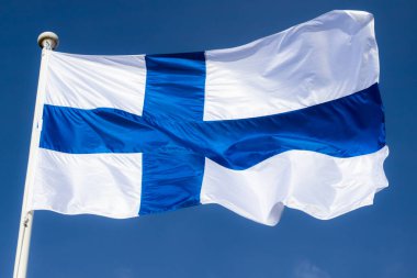 Mavi gökyüzüne karşı esen Finlandiya ulusal bayrağı