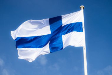 Mavi gökyüzüne karşı esen Finlandiya ulusal bayrağı